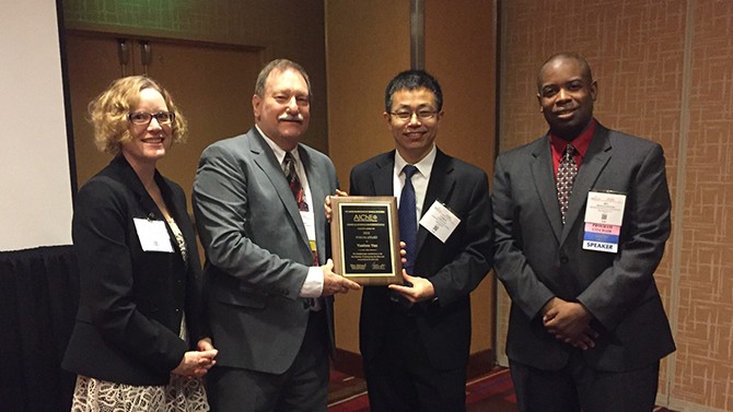 Four people holding plaque